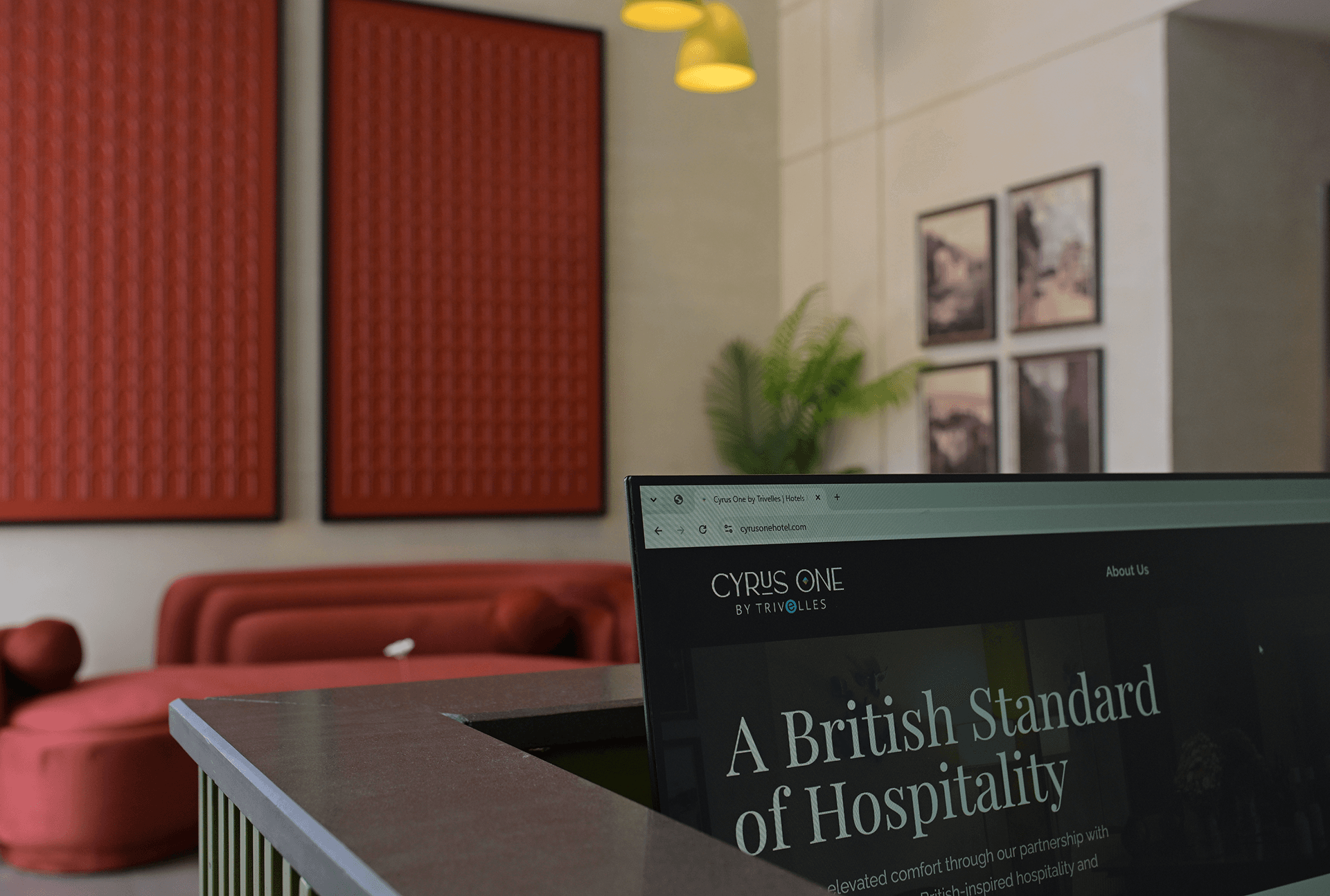 Cyrus One by Trivelles website open on a laptop screen inside the hotel lobby, with the tagline "Explore Beyond Your Stay"