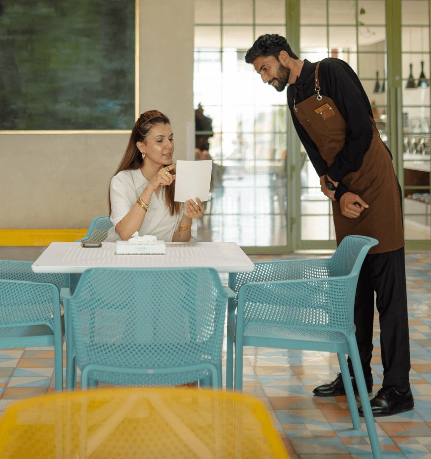 A Cyrus One staff member attending to a seated guest at a café table, reflecting the hotel's attentive hospitality in Islamabad.